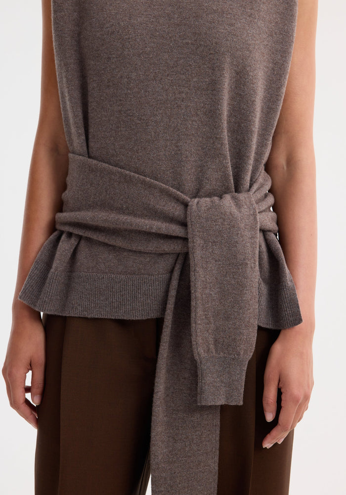 Double-layered knit top in mud melange, featuring a sleeveless design, turtleneck underlayer, tie-sleeve details, and a crewneck overlay tied at the waist.