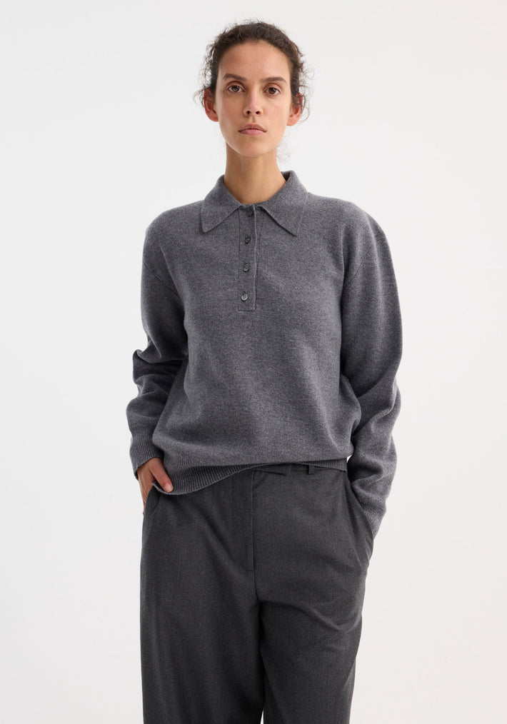 Woman wearing a Compact knitted polo in mid grey melange, featuring a polo collar and button placket, paired with loose-fit trousers.