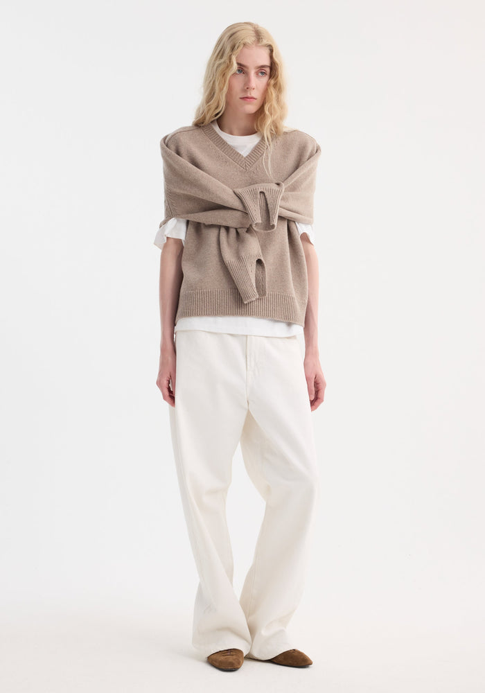 Model wearing Sleeve wrap jumper | taupe melange, showcasing its versatile wrap-sleeve design over a white tee, paired with loose-fit trousers and suede flats.