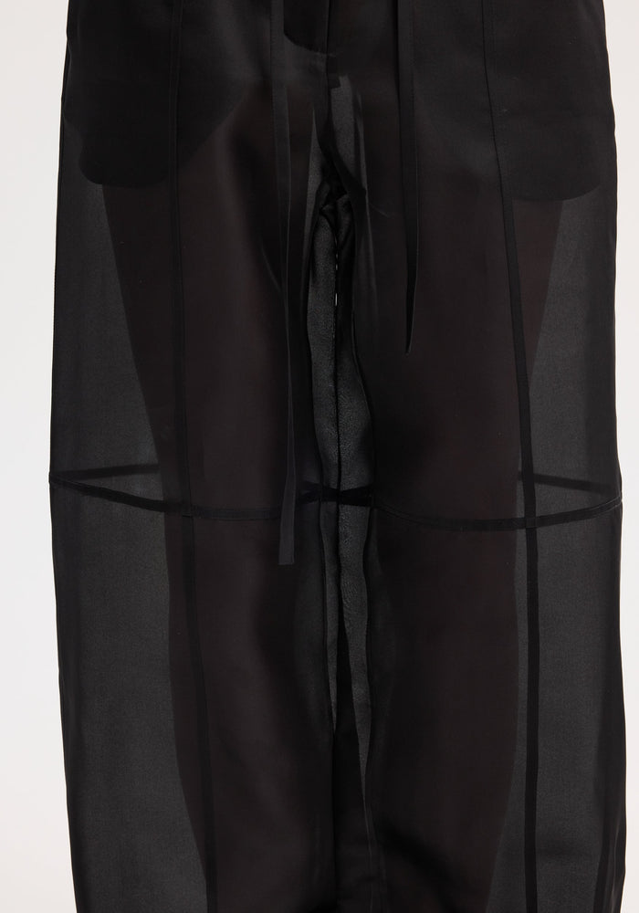 Organza silk parachute trousers in black, featuring sheer silk organza fabric, wide legs, and a drawstring waist, displaying elegance and fluidity.