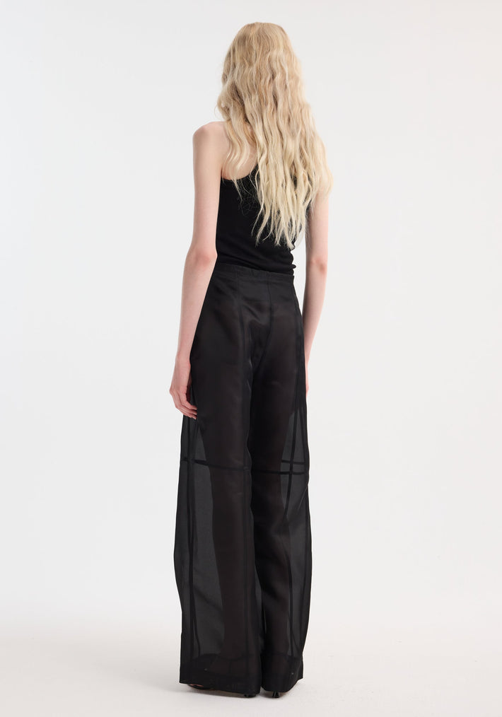 Model wearing Organza silk parachute trousers, showcasing sheer wide-leg design with drawstring waist, layered over opaque shorts, highlighting fluid movement and elegance.
