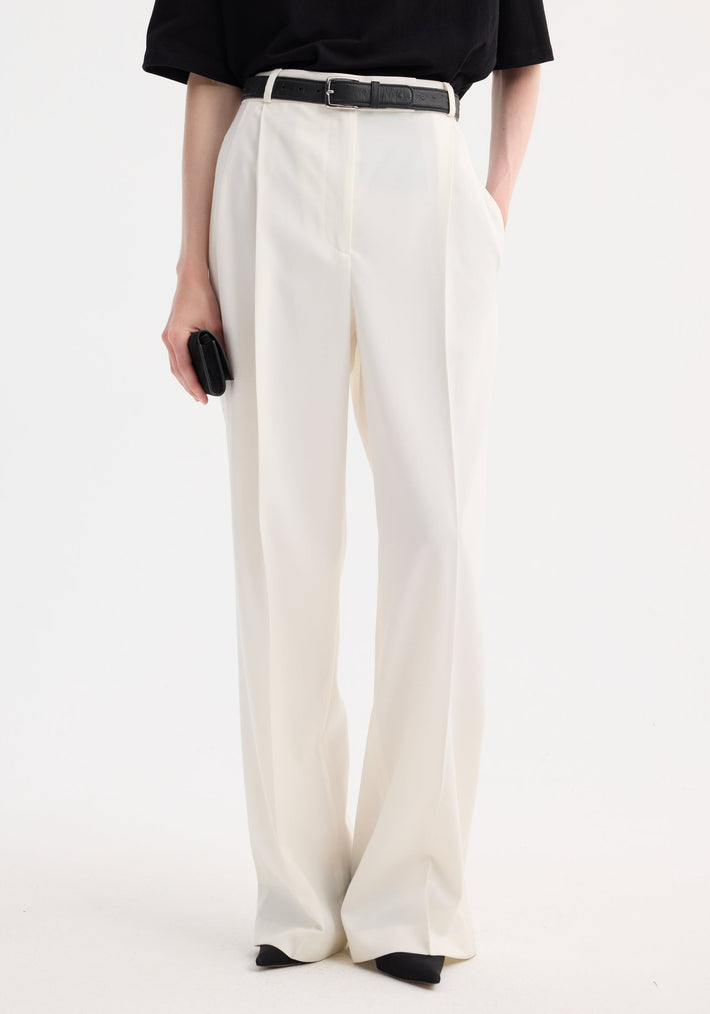Mid-waist tailored trousers in off white wool blend, featuring a high-waisted fit, wide-leg design, and double pleats, paired with a black belt.