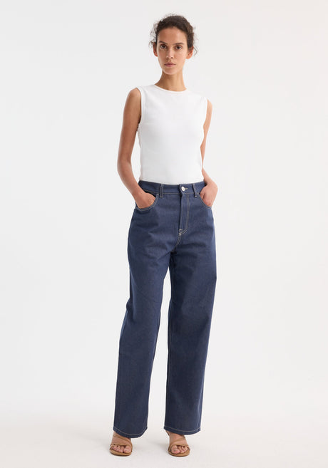 Woman wearing Signature baggy fit raw denim jeans with a low-waist, wide-leg design and a ribbed tank top, styled with tan heeled sandals.