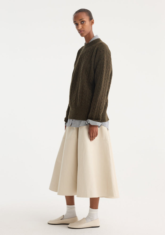 A-line leather skirt | chalk showcased in a profile view. Features croco-embossed soft leather panels, worn with an olive sweater and loafers.