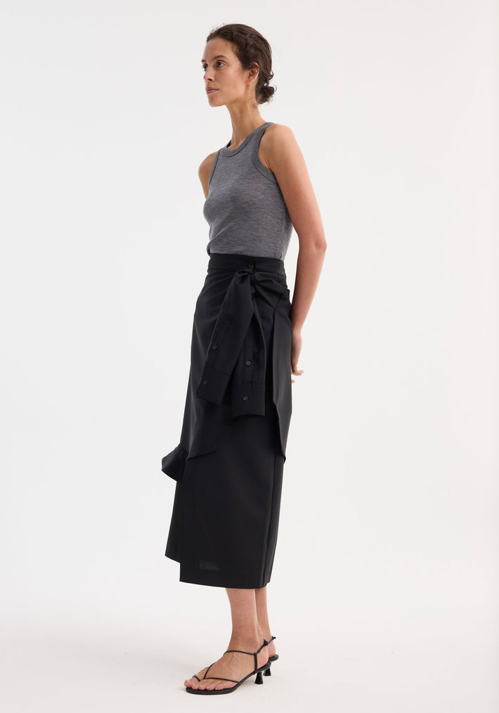 Young woman in a shirt wrap skirt with layered construction and waist tie sleeve detail, styled with a heather-gray tank top and black sandals.