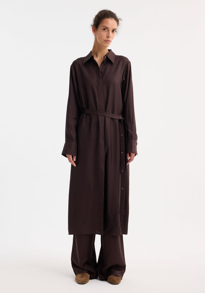Model wearing Silk open back wrap dress in mahogany, featuring a button-down front, wrap tie, and wide-leg trousers, styled with suede slip-on shoes.