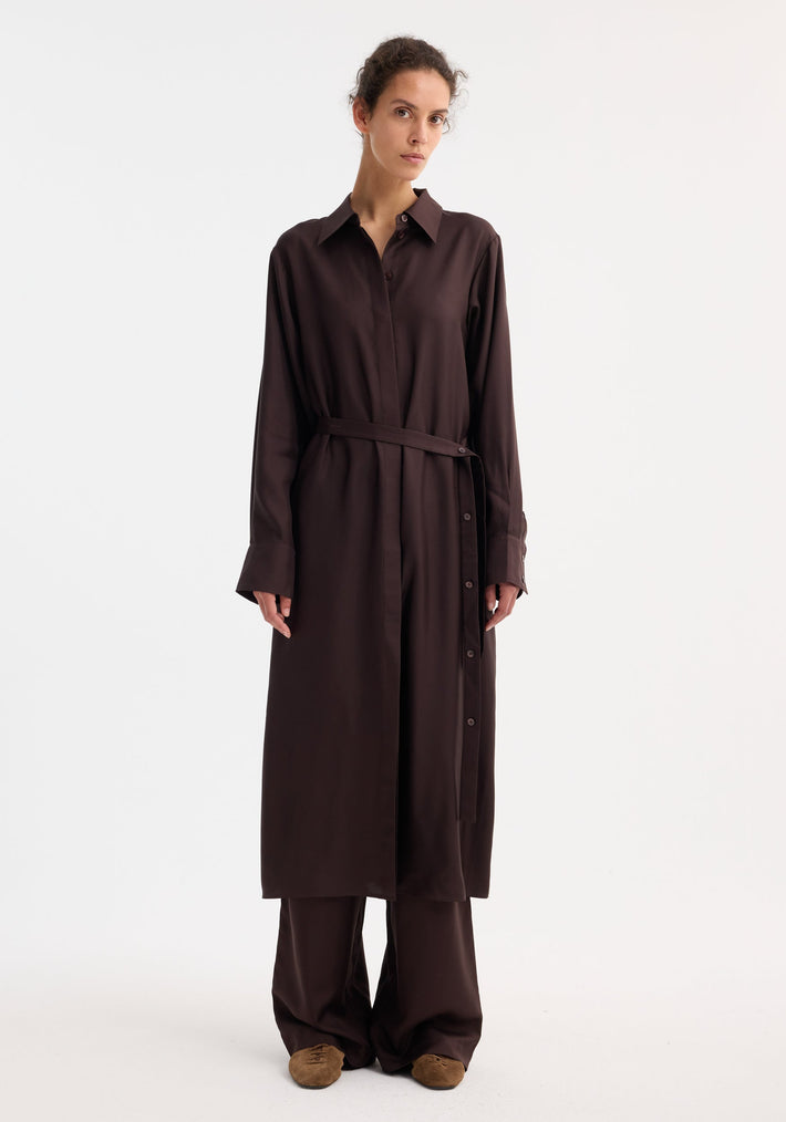 Model wearing Silk open back wrap dress in mahogany, featuring a button-down front, wrap tie, and wide-leg trousers, styled with suede slip-on shoes.