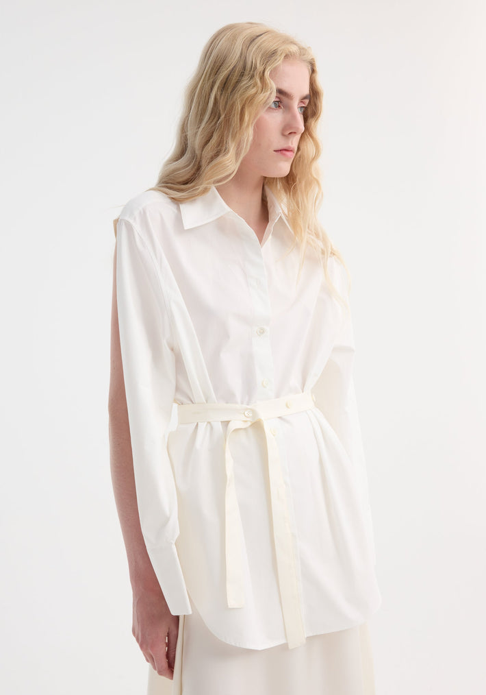Poplin silk combined gilet-dress in optic white on model, featuring a deconstructed style with open armholes, buttoned wrap belt, and layered cotton-silk design.