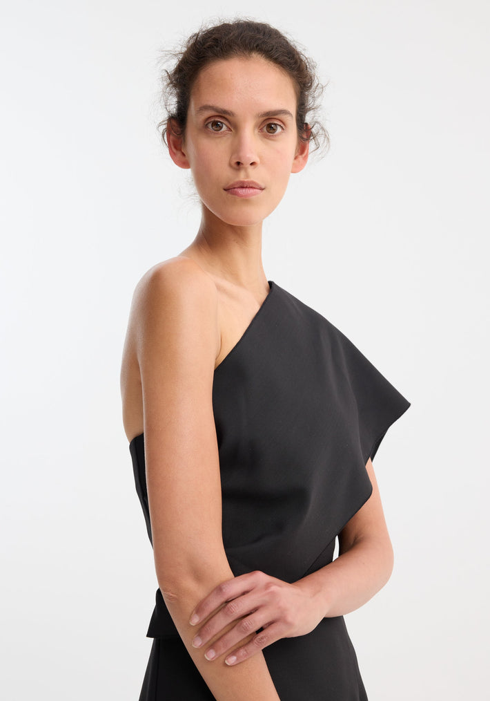 Young woman models the Short sculptural sash dress, showcasing its asymmetric draped sash and sleek fit, highlighting the garment's structured yet fluid design.