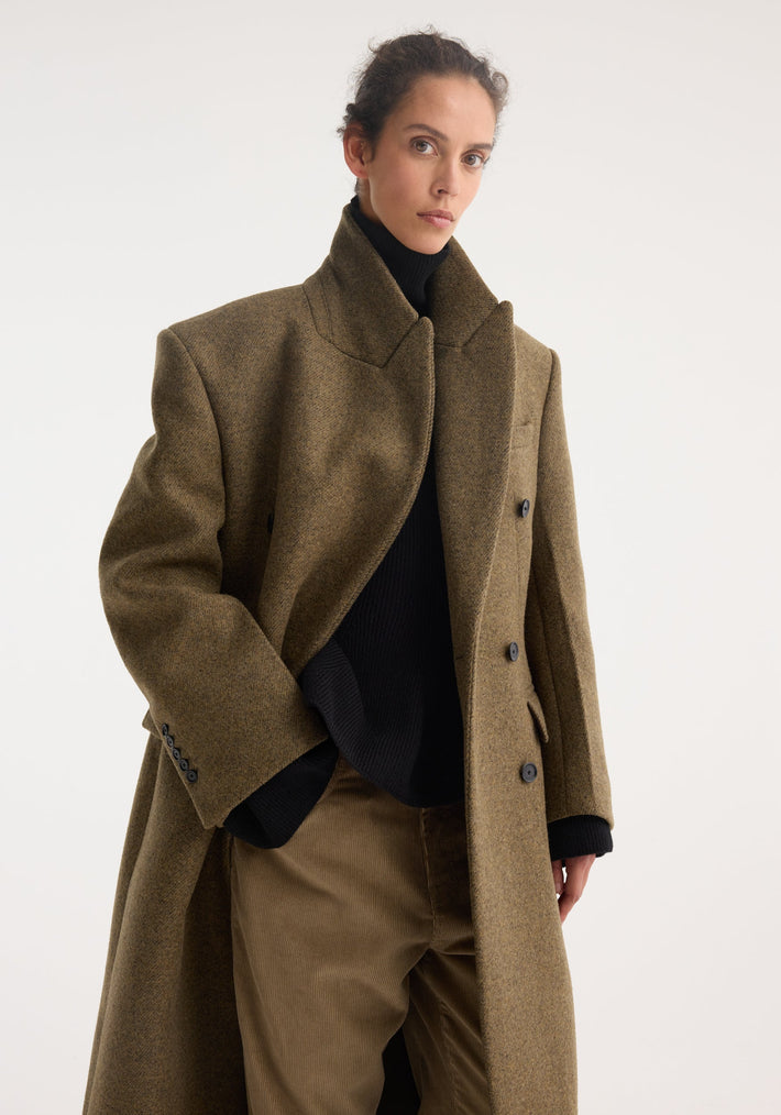 Hourglass wool coat | forest melange: Model wears oversized, double-breasted coat with strong shoulders over black turtleneck and light-brown corduroy pants against a plain backdrop.
