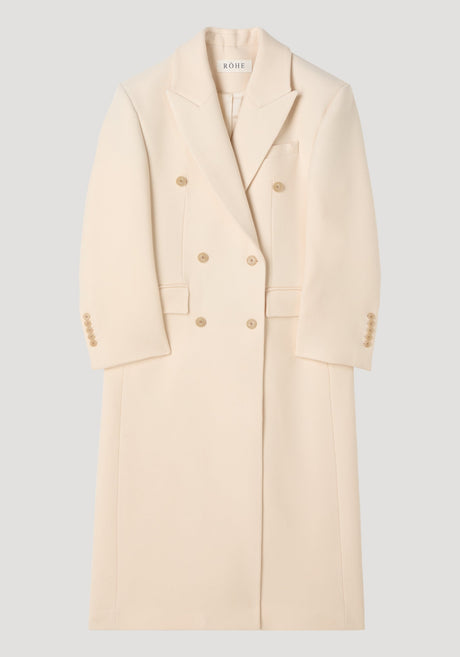 Hourglass wool coat in off white with double-breasted design, peaked lapels, hip flap pockets, and a full-length skirt, showcasing a feminine, structured silhouette.