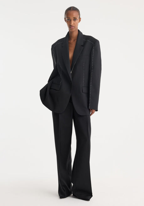 Model wearing Contrast detail blazer in black, showcasing oversized fit, unbuttoned style, contrast stitching, and matching wide-leg trousers, highlighting minimalist, structured design.
