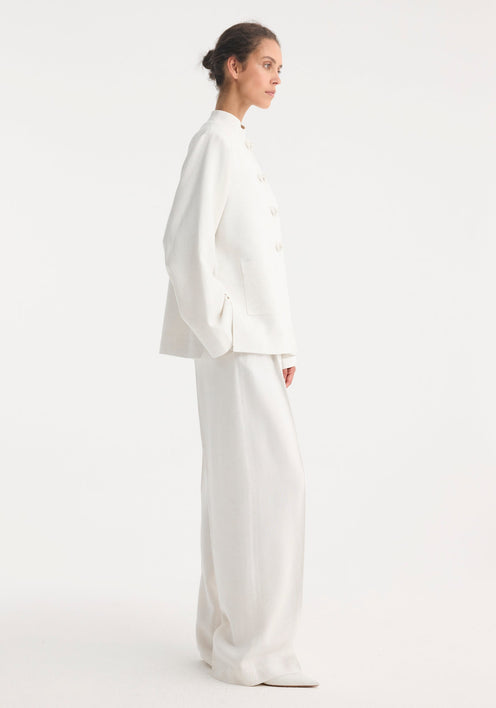 Person wearing a minimalist Mandarin jacket 'Marie' in winter white, featuring wide sleeves, pankou closures, and patch pockets, paired with matching wide-leg trousers.