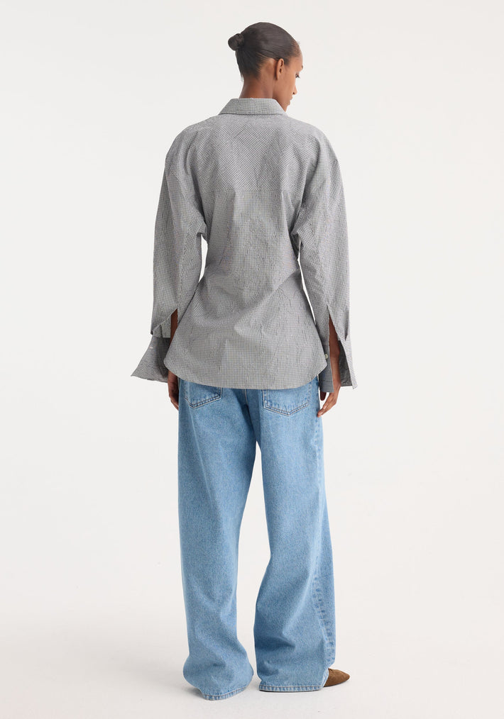 Crushed checked shaped shirt in mini grey check, with a soft sculpted silhouette, worn with light-blue denim jeans, seen from behind, studio shot.