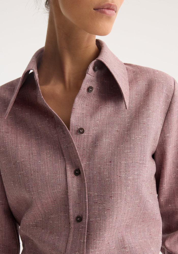 Close-up of a person wearing the Fitted tweed shirt in mauve melange, showcasing its textured fabric, sharp collar, and dark button placket.