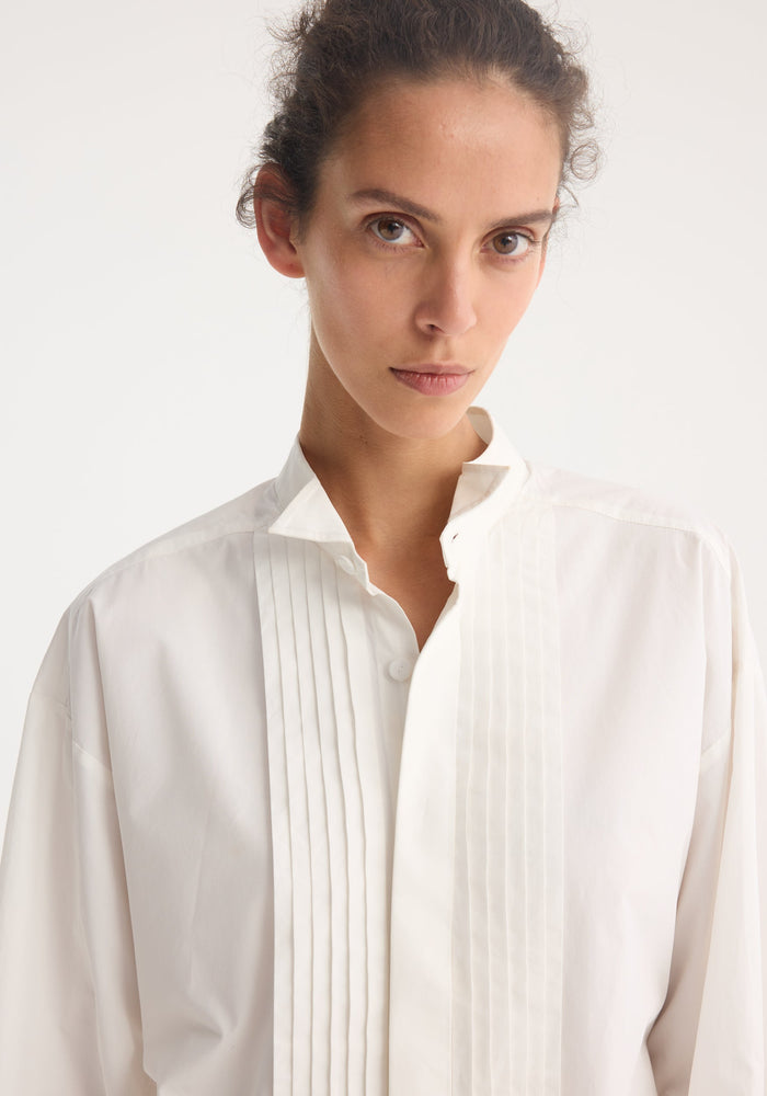 Tuxedo wired shaped shirt in optic white, featuring pintuck pleats, a mandarin collar, and statement cuffs. Model wears size EU 36.