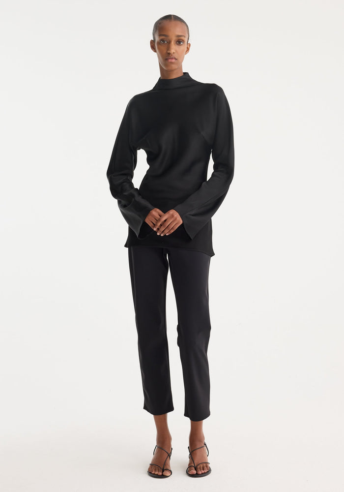 Model wearing a Satin waisted top | black, featuring a mock neck, long flared sleeves, and a slim-fit design with a seamless back zip closure.