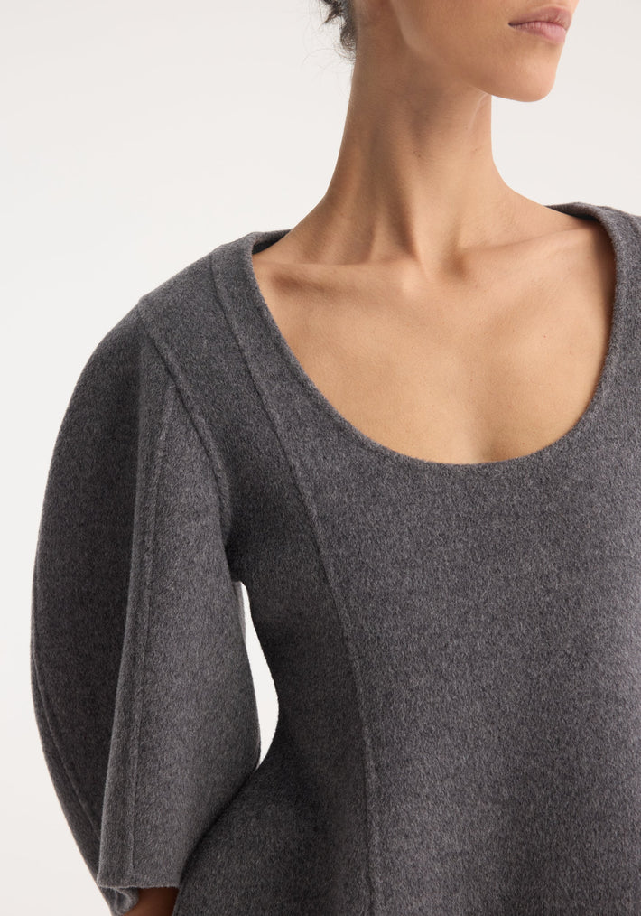 A model wears the Sculptural double-faced top in mid grey melange, featuring a scoop neckline, elbow-length balloon sleeves, and a structured peplum silhouette.