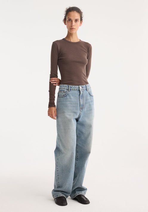 Model wearing the Fine merino long sleeve in brown melange, featuring a crew neck and fitted silhouette, paired with light-blue high-waisted jeans and black loafers.