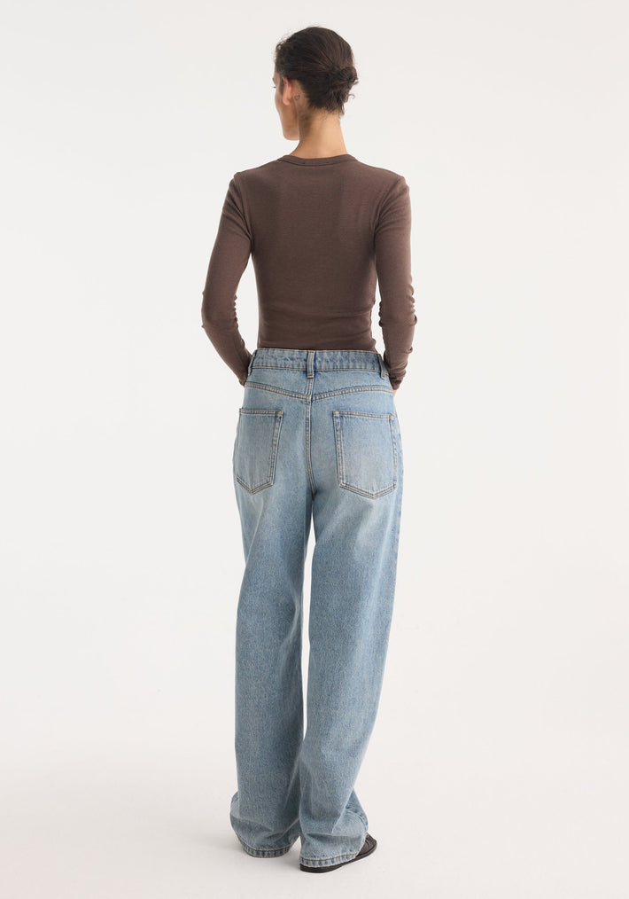 Fine merino long sleeve in brown melange, worn by a person with a tight bun, showcasing its fitted silhouette tucked into wide-leg denim jeans.