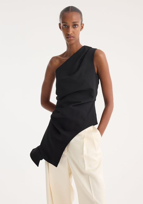 Model wearing Reimagined one shoulder top | black with asymmetrical drape, revealing an upside down collar, paired with wide-leg trousers and pointed-toe shoes.