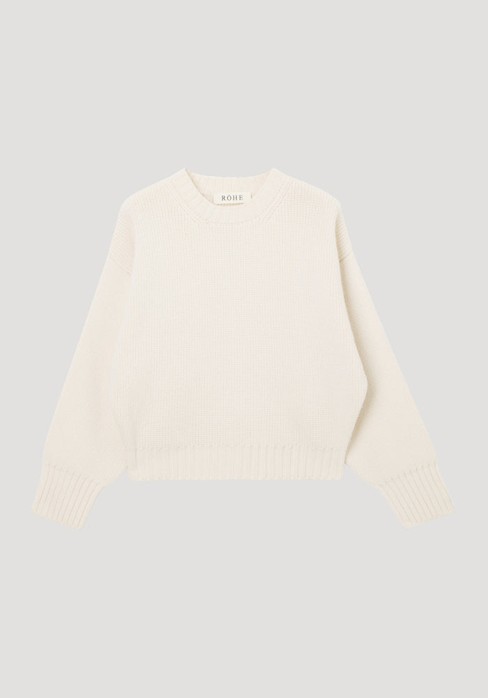 Sculptural compact crewneck | off white: Cream knit sweater with a crew neckline, dropped shoulders, ribbed cuffs, and hem, laid flat. Made of 100% wool by Italian artisans.