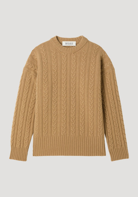 Cable knit jumper in camel with oversized fit, featuring a crew neck, long sleeves, and a cable-knit texture. Label reads “RÓHE” at the back.