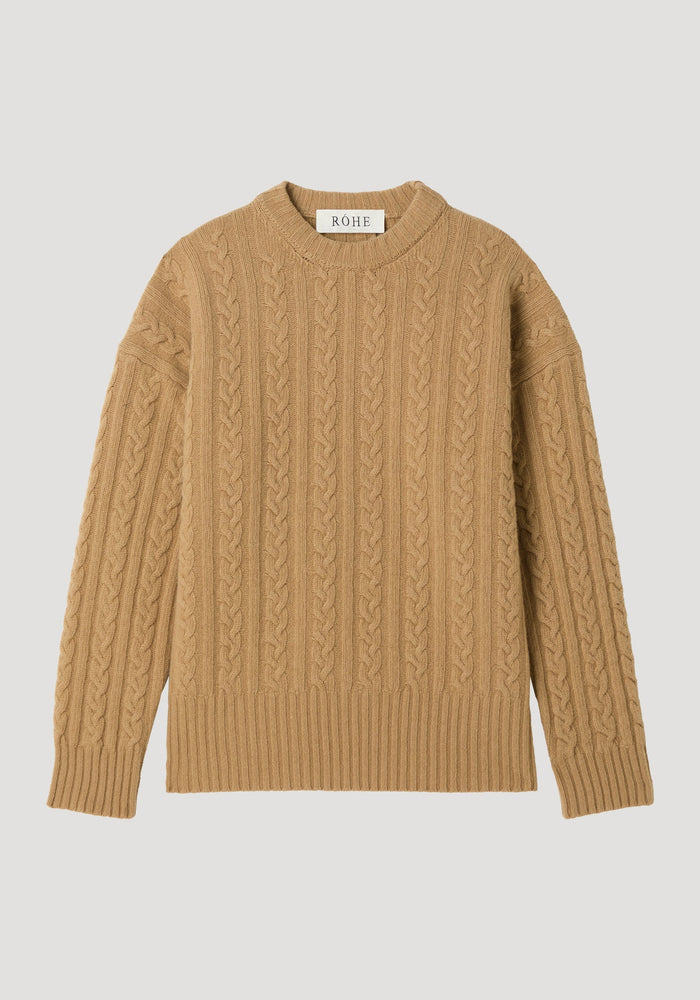 Cable knit jumper in camel with oversized fit, featuring a crew neck, long sleeves, and a cable-knit texture. Label reads “RÓHE” at the back.