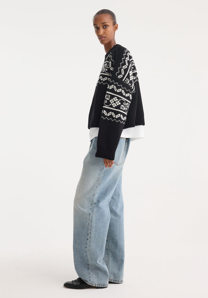 Model wearing Fair-isle knitted jumper | black, with chunky knit, boxy fit, cropped silhouette, over a white T-shirt, paired with light-wash wide-leg jeans.