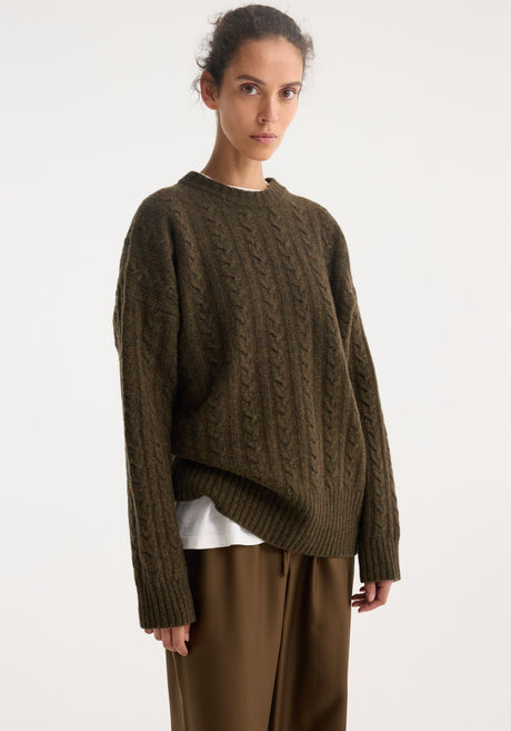 Model in oversized Cable knit jumper | forest melange, with a textured pattern and dropped shoulders, paired with wide-leg pants and loafers.