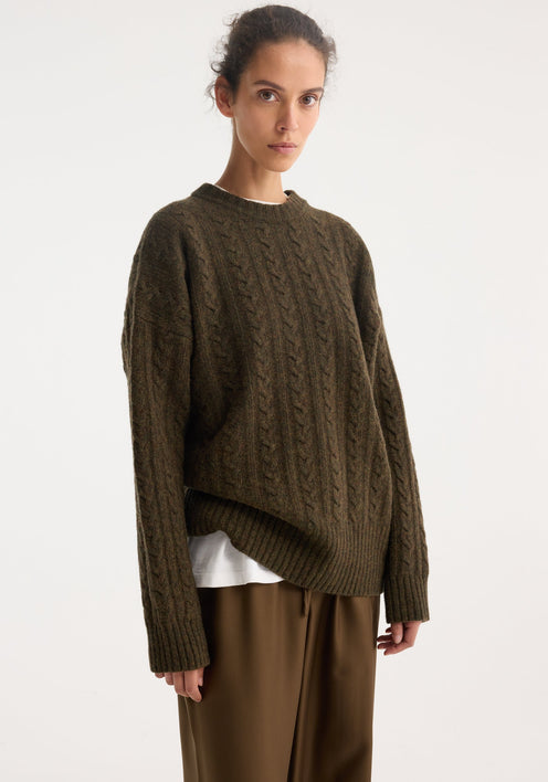 Model in oversized Cable knit jumper | forest melange, with a textured pattern and dropped shoulders, paired with wide-leg pants and loafers.