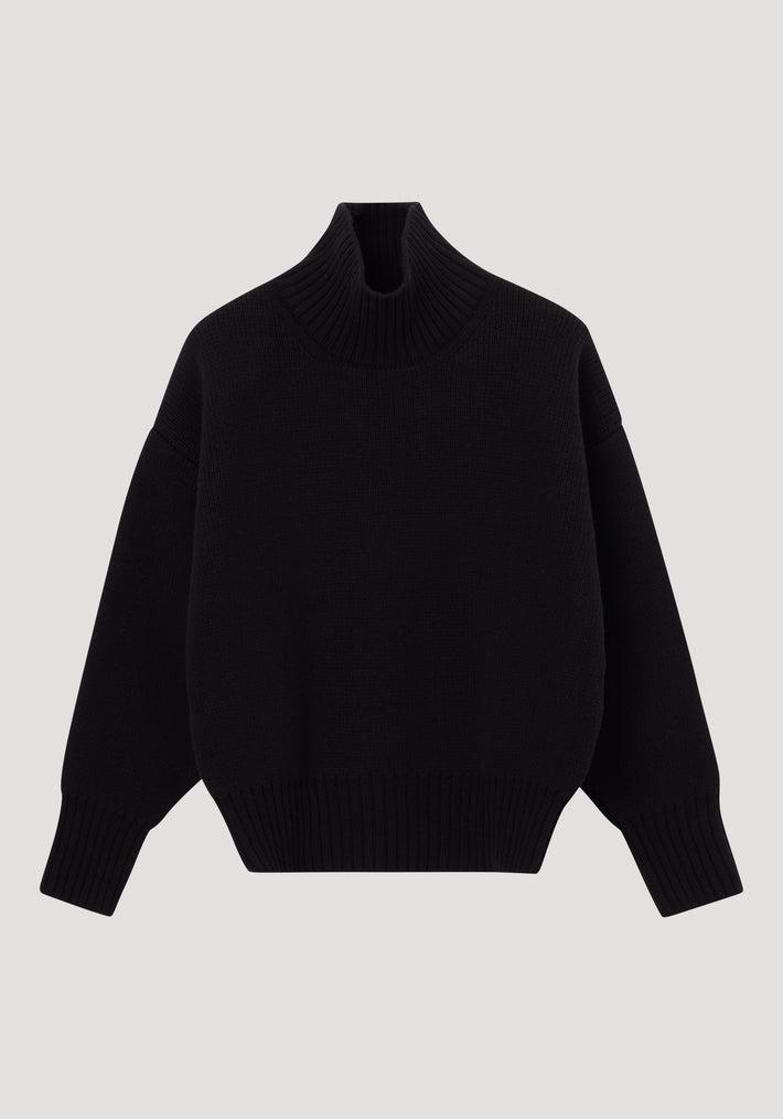 Sculptural compact turtleneck | black: A plain black knit sweater with a high collar, dropped shoulders, long sleeves, and ribbed neck, cuffs, and hem.