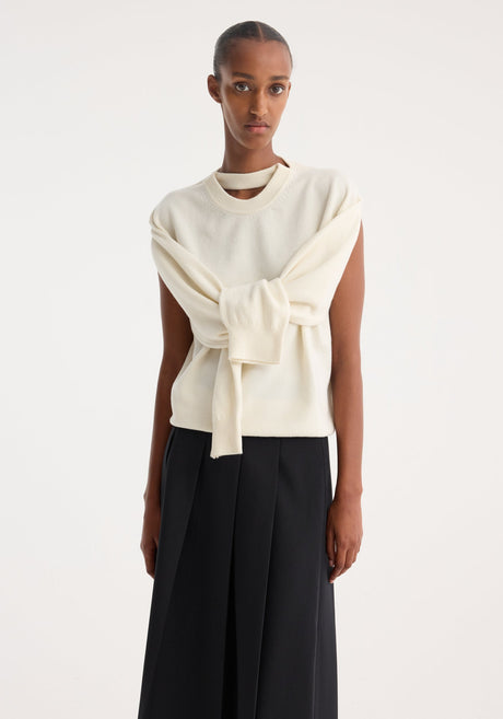 Model in minimalist attire showcasing a Crewneck with open neck | off white, featuring draped sleeves and a key-hole detail, paired with a black midi skirt.
