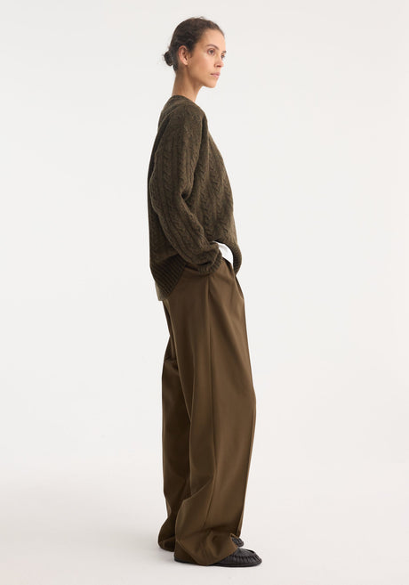 Model wearing Signature tailored trousers in forest, showcasing a wide-leg, mid-waist fit with front pleats, paired with an oversized cable-knit sweater.
