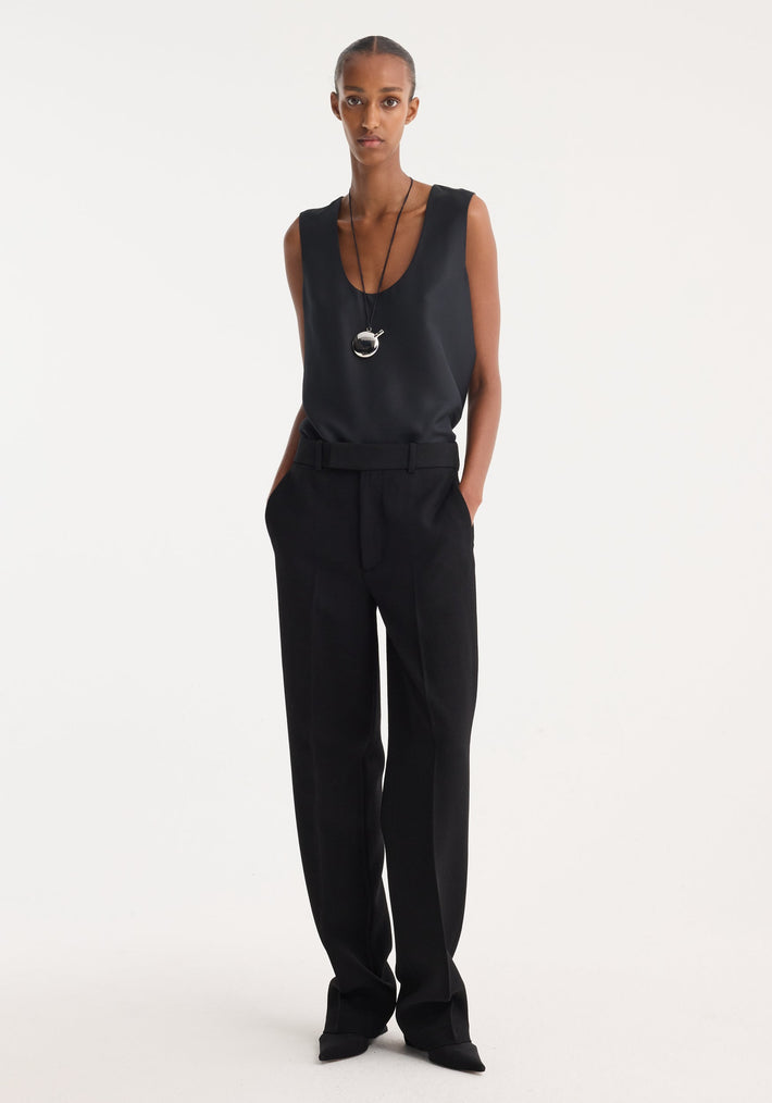 A slender person wears Straight leg trousers | black, showcasing high-waisted tailoring, sharp pleats, and side pockets, paired with a minimalist black scoop-neck top.