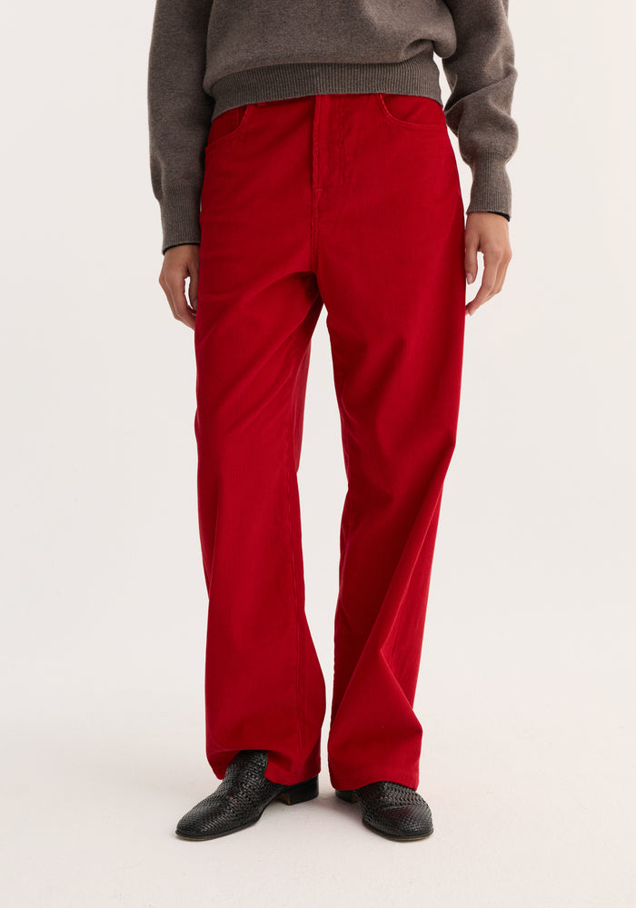 Relaxed corduroy trousers in Rosso, featuring a wide-leg design and denim-inspired details, paired with woven black shoes and a gray-brown knit sweater hem.
