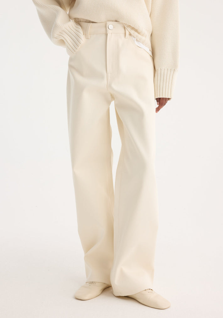 Person wearing Compact cotton trousers | off white, showcasing high-waisted, wide-leg design, paired with a tucked chunky knit sweater and pointed-toe loafers, one hand in pocket.