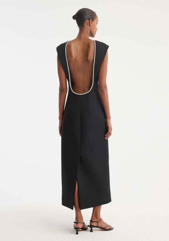Woman in an Open back appliqué dress | black, featuring a deep U-shaped back with crystal trim, tailored silhouette, and center back slit.