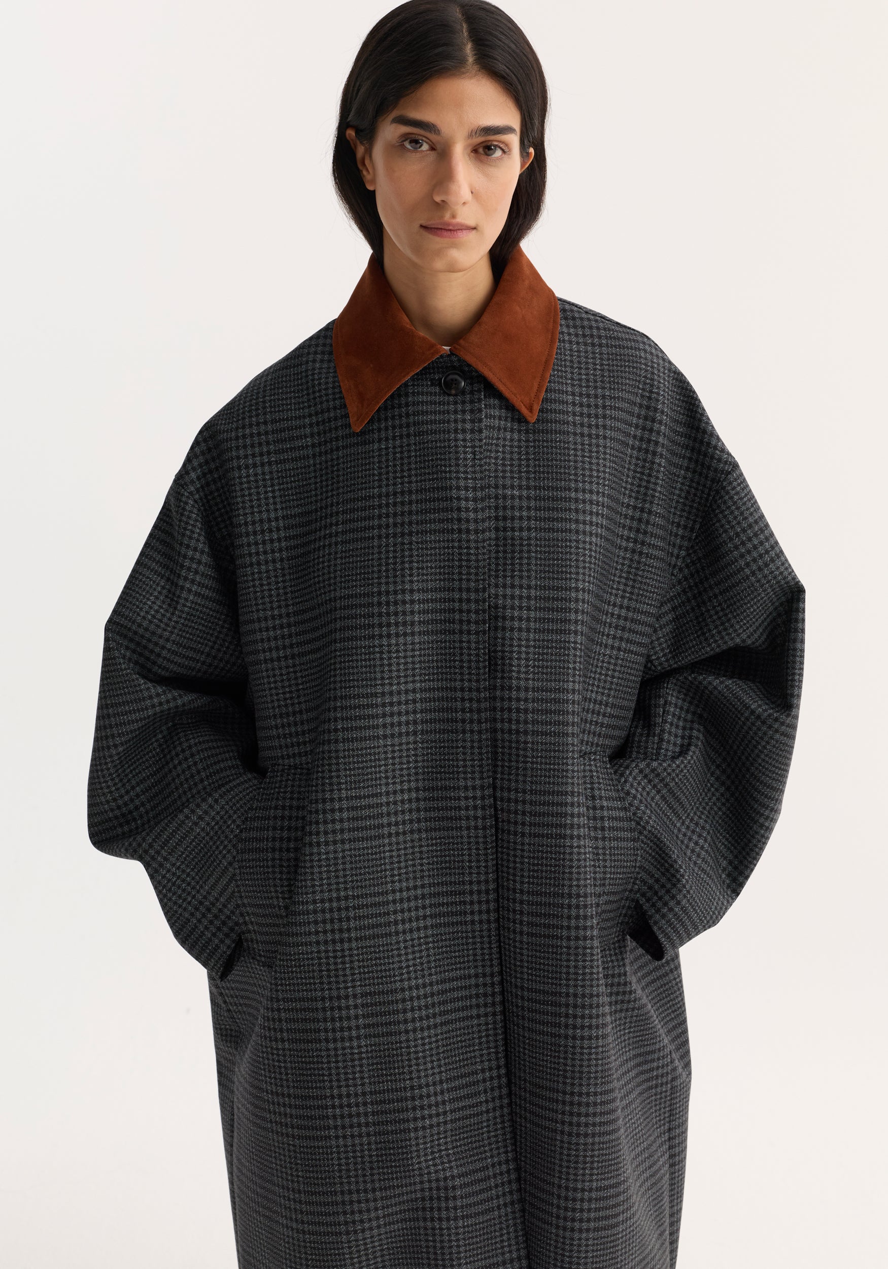 Woman wearing a black and grey check coat with a contrasting brown suede collar, styled with pockets and a classic button-up front, Suede collar check coat | black / grey check.