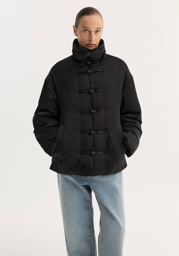 Padded puffer jacket | black with a high funnel collar, pankou closures, slanted pockets, worn with light-wash jeans. Model is 178cm, size 36.