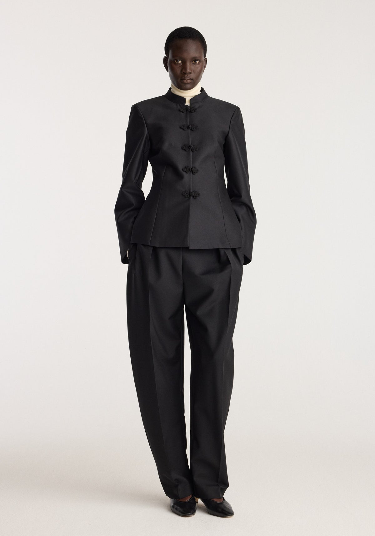 Sculptural pankou closure blazer | black worn by a model with a high collar and traditional knot closures styled with matching wide leg trousers