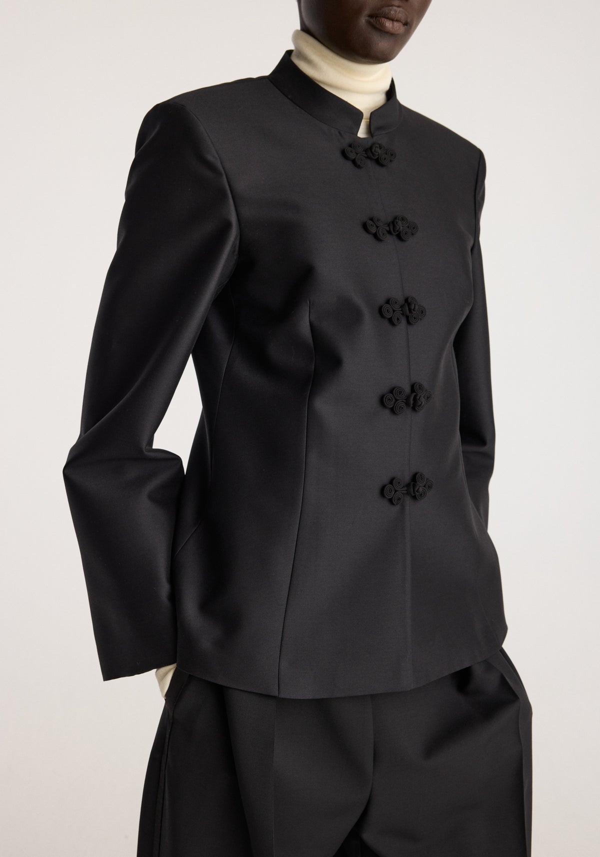Sculptural pankou closure blazer | black shown on a model with a high stand collar, structured shoulders, long sleeves, and decorative knot closures
