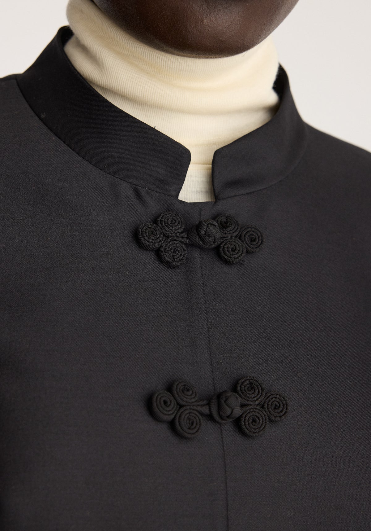 Sculptural pankou closure blazer | black featuring a stand collar and ornate black knotted closures on the front worn over a cream turtleneck