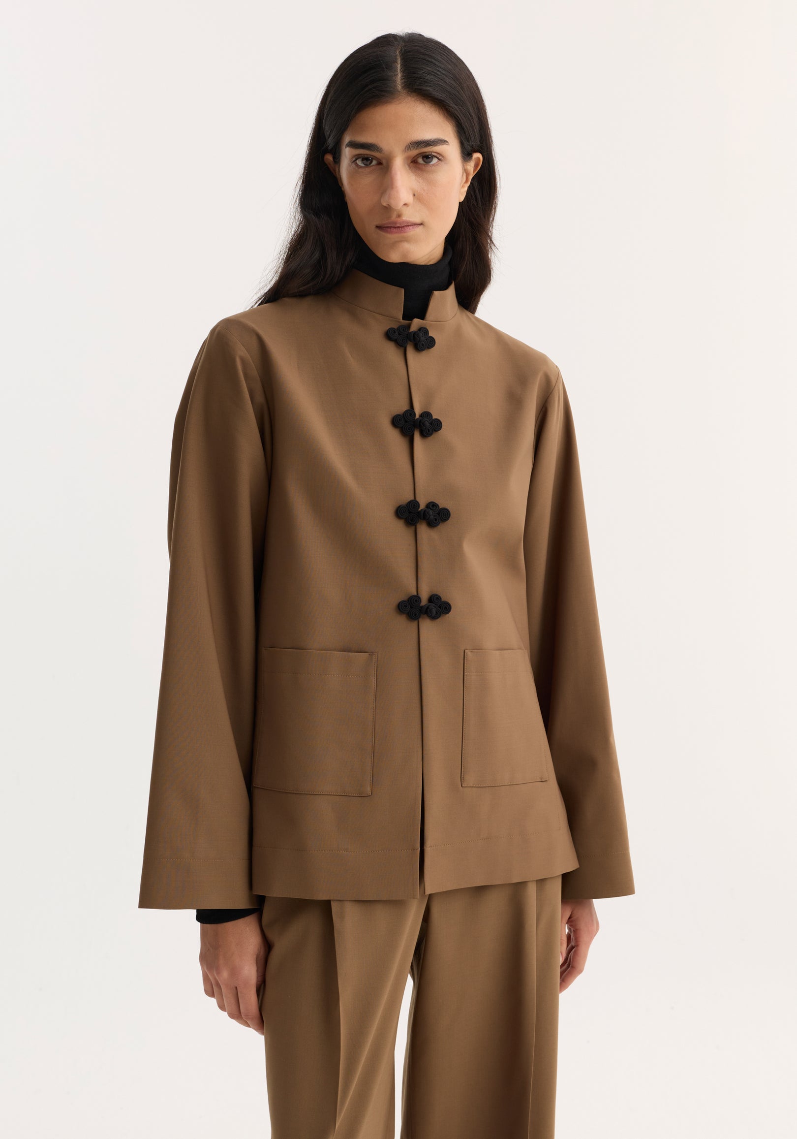 Woman wearing a mocha Pankou closure jacket with black traditional knot closures on the front, paired with matching mocha pants against a plain background.