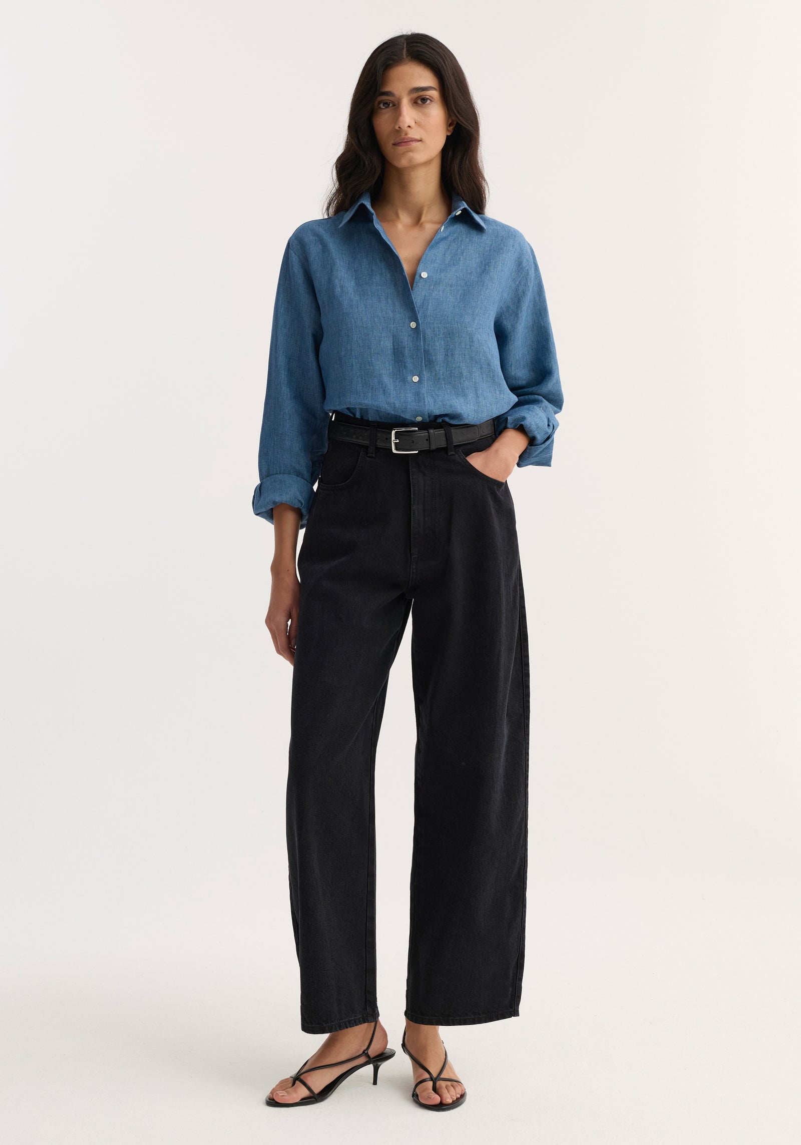 Model wearing Barrel leg denim | black, featuring a high-waisted, loose fit with a curved, slightly cropped barrel-leg silhouette, paired with a simple black leather belt.
