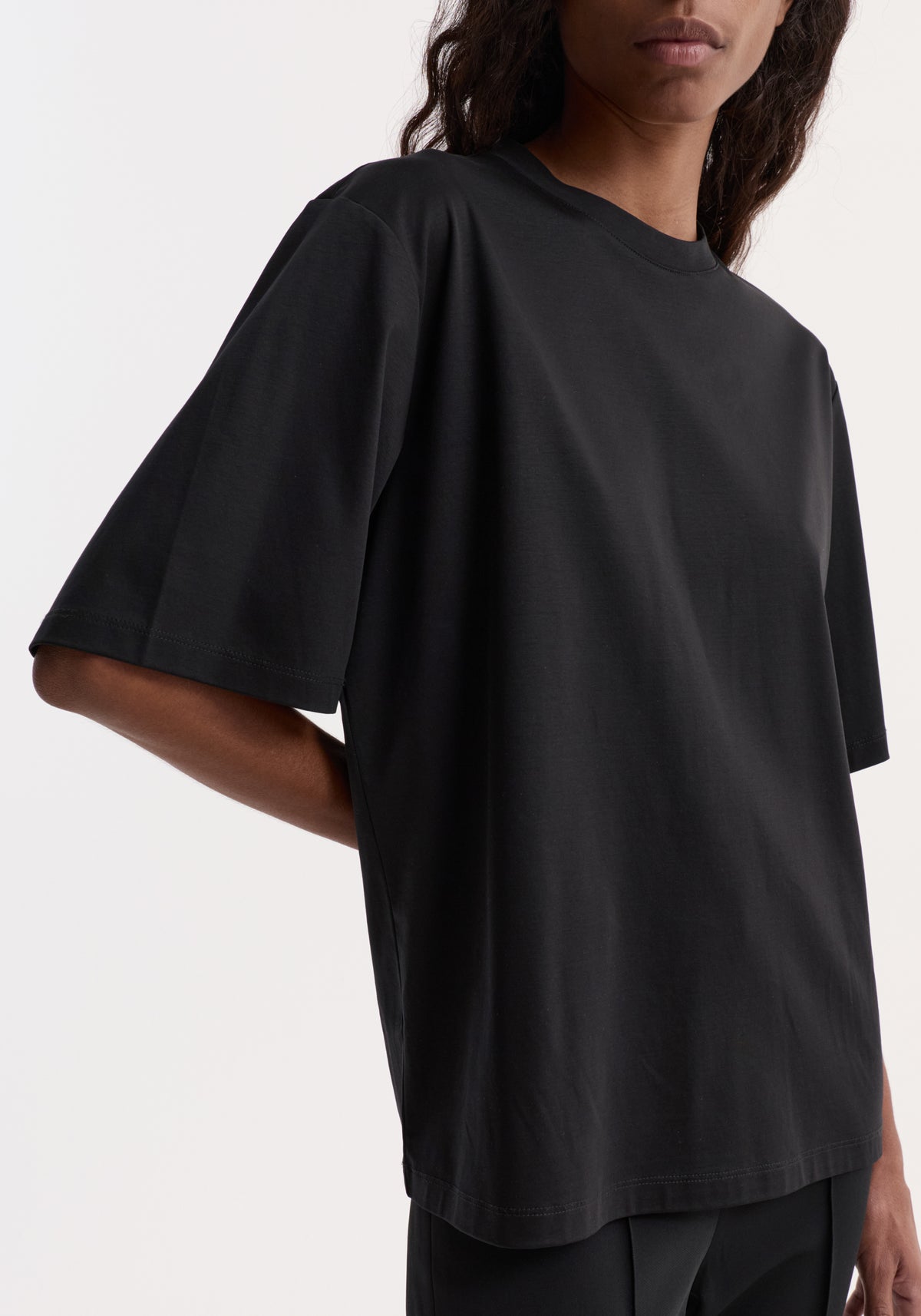 Model wearing Oversized cotton silk t-shirt | black, an oversized black short-sleeve tee with a relaxed fit and curved hem.