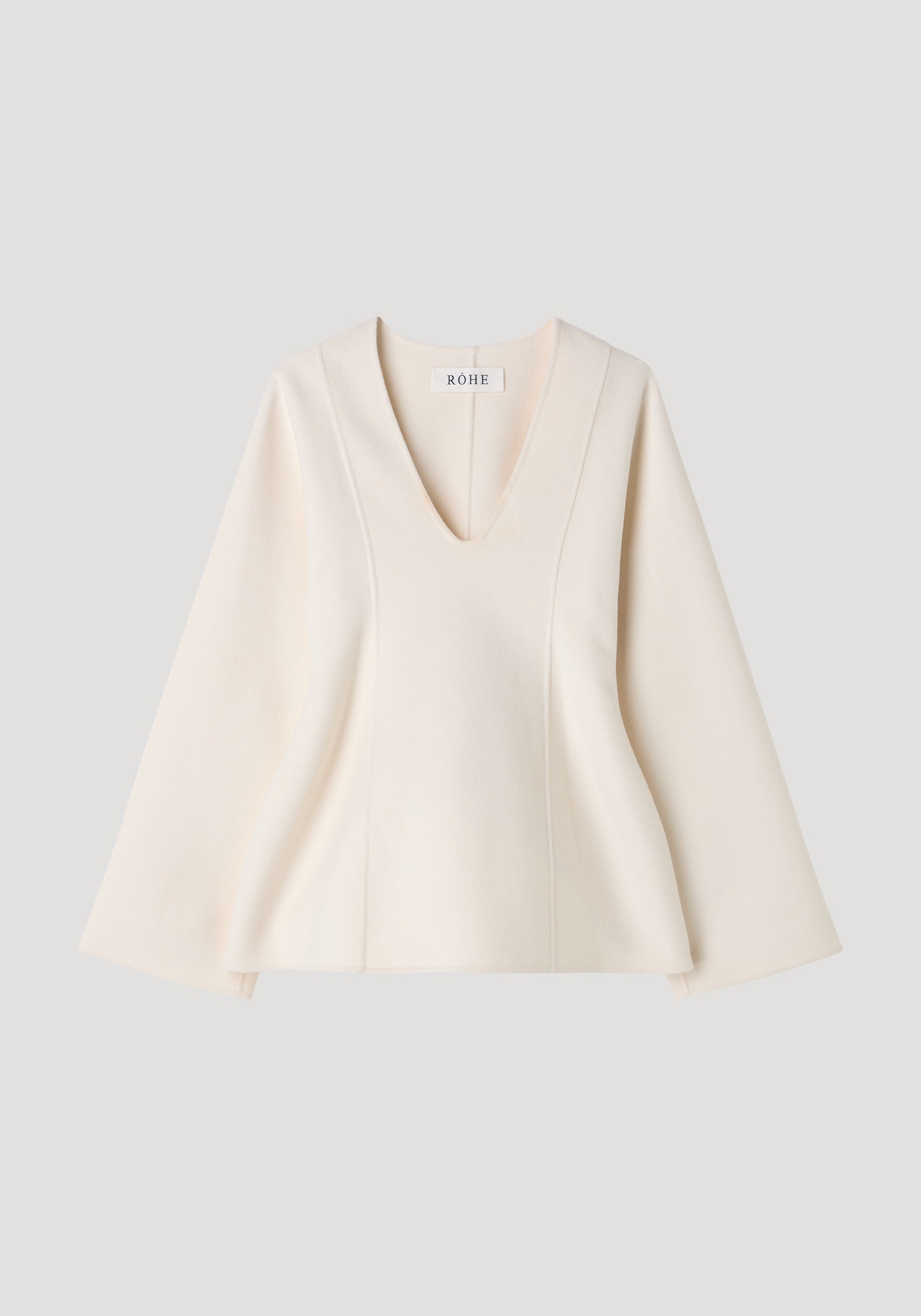 Sculptural long sleeve top | off white, featuring a deep V-neck, structured silhouette, and slightly flared sleeves, made from smooth, elegant fabric.