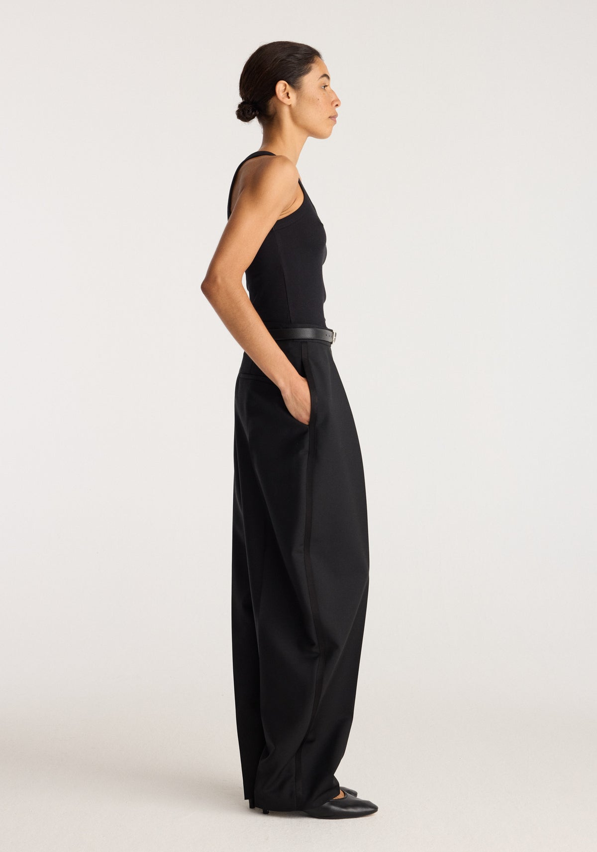Merino scoop neck top | black shown on a model in side profile with a fitted sleeveless silhouette paired with black wide leg trousers