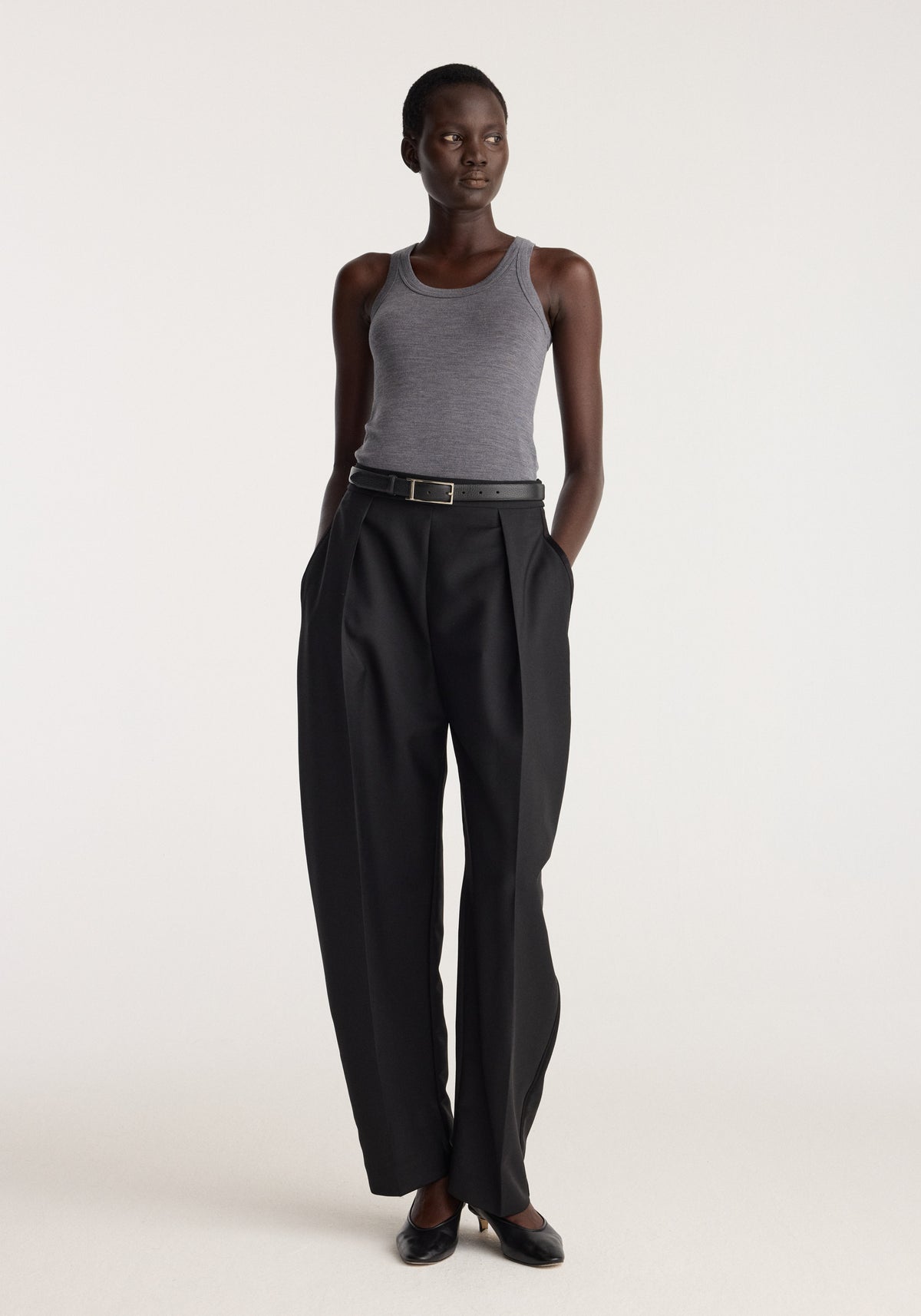 Merino scoop neck top | mid grey melange worn by a model with black tailored trousers and black flats against a neutral background