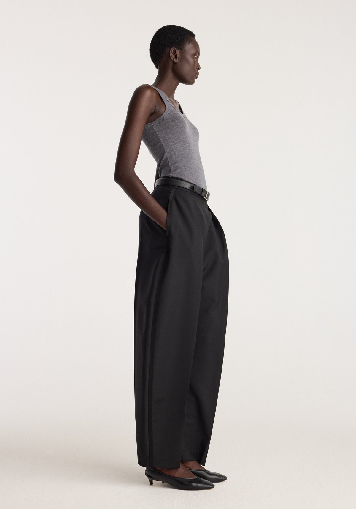 Merino scoop neck top | mid grey melange worn by a model with black high waisted trousers in side profile against a light neutral background
